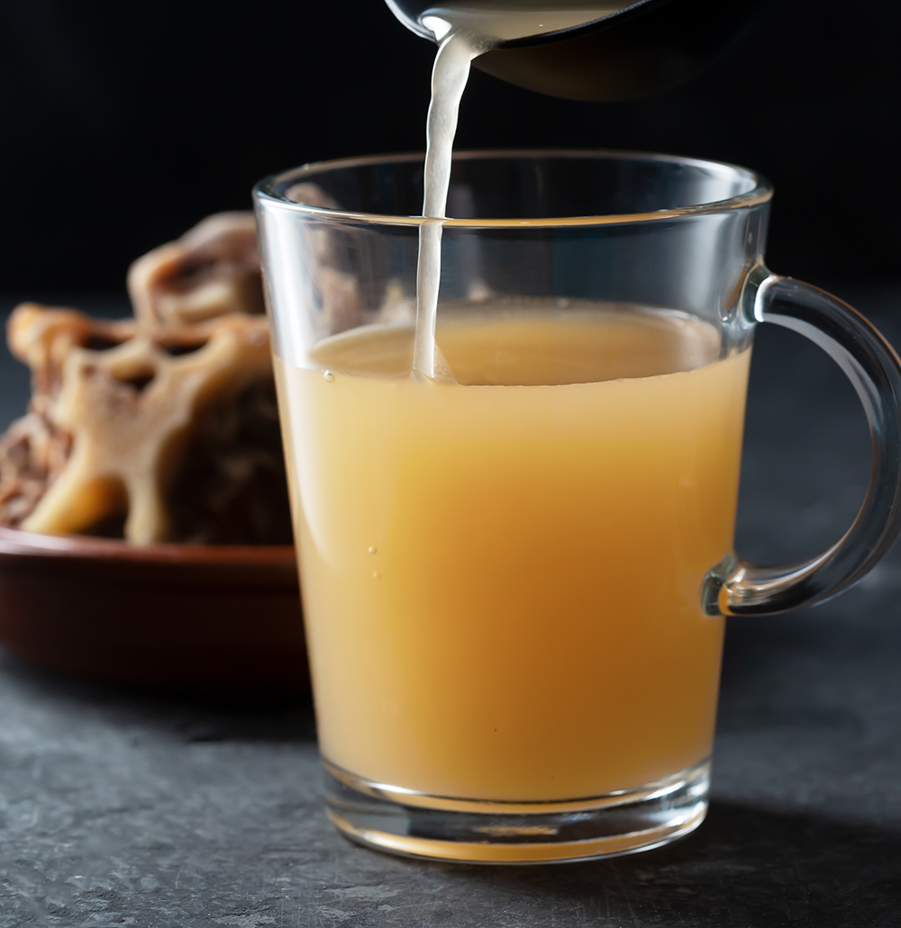 Homemade Beef Bone Broth in Glass Storage Jar on the black background. Bones contain collagen, which provides the body with amino acids, which are the building blocks of proteins