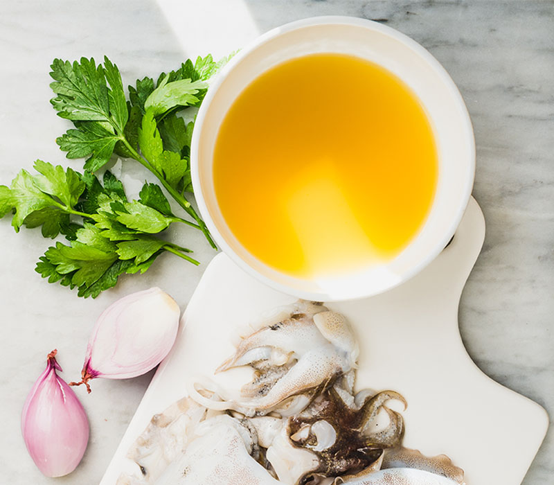 Fish broth in a bowl with parsley, onion and squid served on the side - Scoular