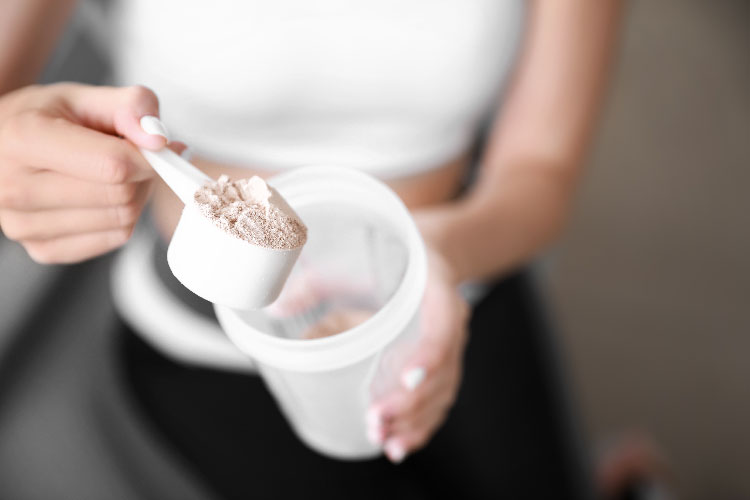 a scoop of protein powder over a container