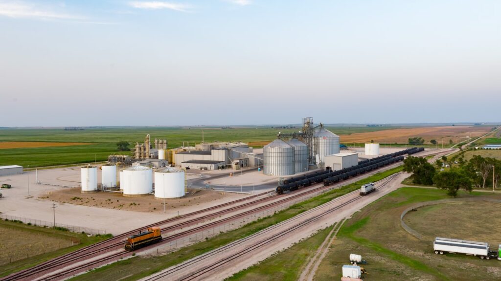 Aerial view showcasing a grain silo adjacent to train tracks, highlighting agricultural infrastructure and transportation